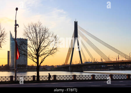 Riga, Lettonie. SwedBank Tower et Vansu pont sur la rivière Daugava au coucher du soleil. Banque D'Images