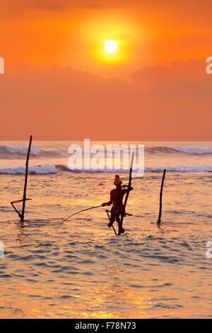 Pêcheurs sur pilotis au coucher du soleil tropical, Koggala Beach, au Sri Lanka, en Asie Banque D'Images