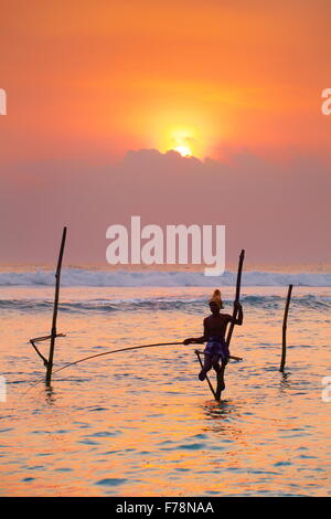 Sri Lanka - pêche pêcheur sur pilotis dans la mer, coucher du soleil tropical à Koggala Beach, en Asie Banque D'Images