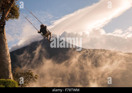Silhouette d'un heureux'fille se balançant sur une balançoire au-dessus des montagnes des Andes, volcan Tungurahua en arrière-plan Banque D'Images