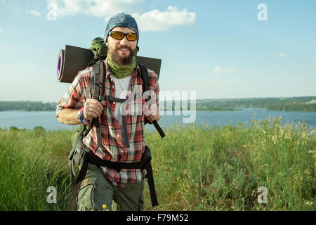 Young caucasian man with backpack marche sur le haut de la colline Banque D'Images