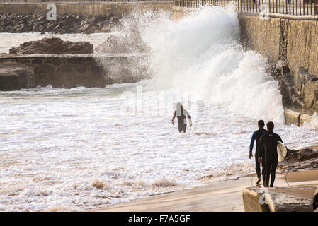 3 surfers à marcher le long de son avec le fracas des vagues, Cascais, Portugal Banque D'Images