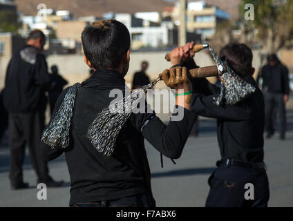 Les garçons chiite iranien couvert de boue se battent avec des chaînes de fer pour commémorer Achoura, le jour de la mort de l'Imam Hussein, province du Kurdistan, Bijar, Iran Banque D'Images