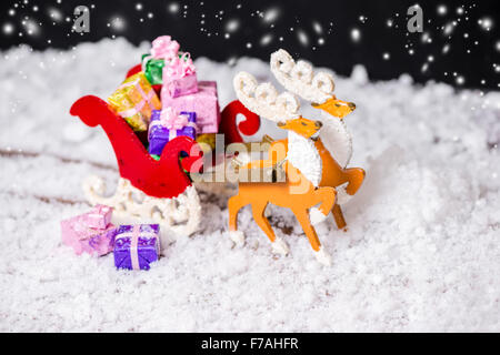 Composition de Noël Décoration renne et Santa sleigh avec cadeaux dans les traces de neige sur fond noir, gros plan Banque D'Images