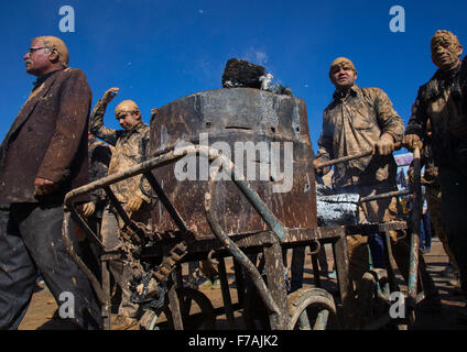 Les hommes musulmans chiites iraniens couvert de boue poussant un chariot avec le feu lors d'Ashoura Jour, province du Kurdistan, Bijar, Iran Banque D'Images