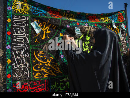 Les femmes musulmanes chiite iranien couvert de boue les billets de banque sur un drapeau au cours d'Ashura, le jour de la mort de l'Imam Hussein, province du Kurdistan, Bijar, Iran Banque D'Images