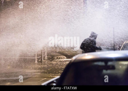 Aberystwyth, Pays de Galles, Royaume-Uni. 27 novembre 2015 Les gens de retourner à leurs voitures en stationnement après avoir vu les lumières de Noël mettez à Aberystwyth town center Trouver l'approche de la marée haute avec de forts vents poussant l'eau de mer sur la promenade et le rendre désagréable pour eux d'entrer dans leurs véhicules. Crédit : Ian Jones/Alamy Live News Banque D'Images