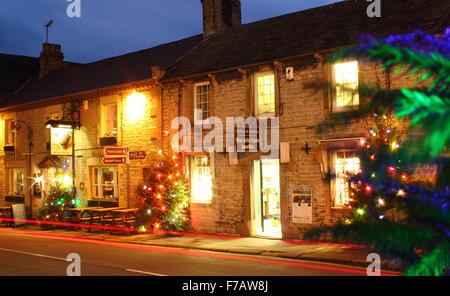 Les arbres de Noël décorés illuminent la rue principale en Castleton ; un village traditionnel dans le Peak District, Derbyshire, Angleterre Banque D'Images