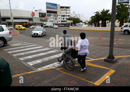 Femme en fauteuil roulant à l'aide de rampe d'accès au passage piétons, chaussée à Miraflores, Lima, Pérou Banque D'Images