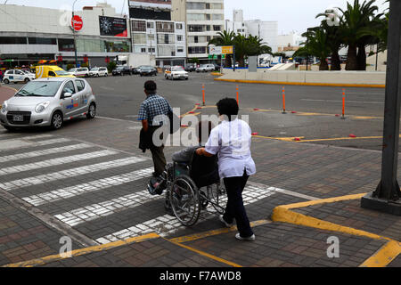 Femme en fauteuil roulant à l'aide de rampe d'accès au passage piétons, chaussée à Miraflores, Lima, Pérou Banque D'Images