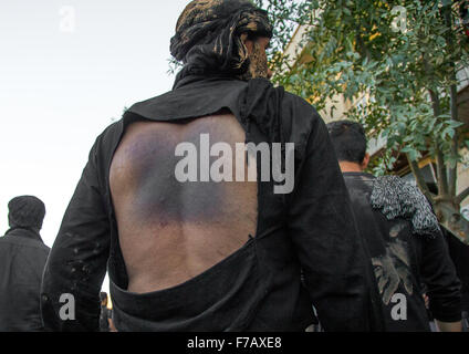 Chiite iranien homme couvert de boue qui a lui-même battu son dos avec des chaînes de fer au cours d'Ashura, le jour de la mort de l'Imam Hussein, province du Kurdistan, Bijar, Iran Banque D'Images