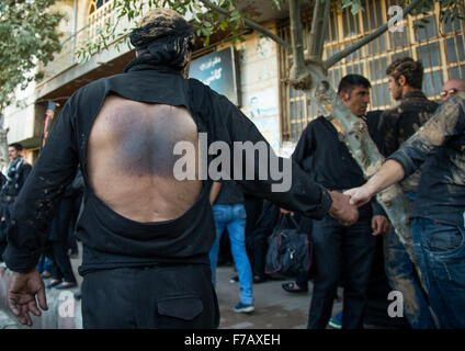 Chiite iranien homme couvert de boue qui a lui-même battu son dos avec des chaînes de fer au cours d'Ashura, le jour de la mort de l'Imam Hussein, province du Kurdistan, Bijar, Iran Banque D'Images