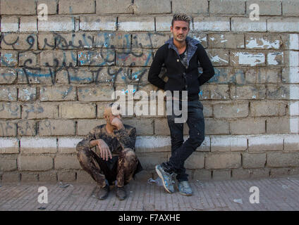 Les hommes musulmans chiites iraniens couvert de boue, appuyé contre un mur après Ashoura Cérémonie, province du Kurdistan, Bijar, Iran Banque D'Images