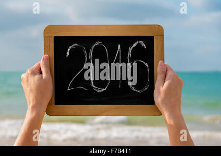 Woman's hands avec tableau noir et chiffres 2016 sur-le contre la mer - concept de nouvelle année, locations et voyage Banque D'Images