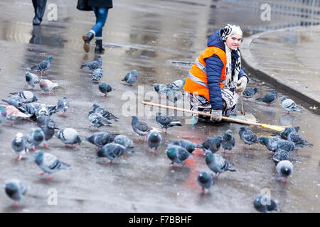 Saint Petersburg, Russie - 18 novembre 2015 : un travailleur de l'hygiène est accroupis parmi les pigeons dans le centre de Saint-Pétersbourg, Rus Banque D'Images