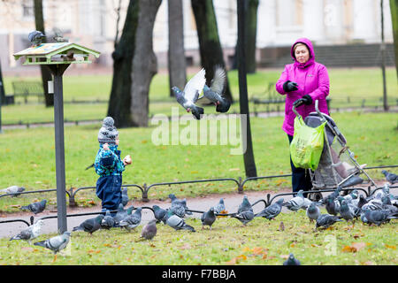 Saint Petersburg, Russie - le 20 novembre 2015 : Une mère et son enfant se nourrissent les pigeons dans un parc à Saint Pétersbourg, Russie. Banque D'Images