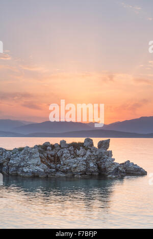 Les rochers s'élèvent de la mer Ionienne dans le Détroit de Corfou près de Kassiopi, Corfou. Le soleil se lève sur l'Albanie. Banque D'Images