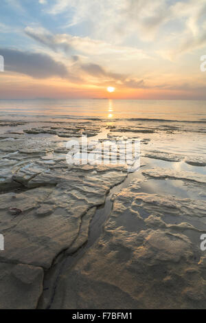 Les rochers s'élèvent de la mer Ionienne dans le Détroit de Corfou près de Kassiopi, Corfou. Le soleil se couche sur la mer. Banque D'Images