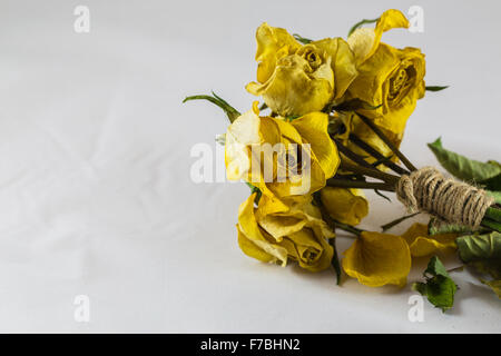 Paquet de roses jaunes sèches liées par de la ficelle de jute sur fond blanc Banque D'Images