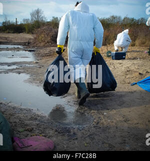 Calais, France. 28 Nov, 2015. Les travailleurs français vêtus de combinaisons blanches de protection de poursuivre l'opération de nettoyage au site migrants à Calais connu sous le nom de la jungle, les travailleurs enlevés supprimés tentes et d'ordures depuis le site et construit de nouveaux points de collecte des ordures. Credit : Duncan Penfold/Alamy Live News Banque D'Images