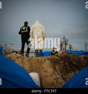 Calais, France. 28 Nov, 2015. Les travailleurs français vêtus de combinaisons blanches de protection de poursuivre l'opération de nettoyage au site migrants à Calais connu sous le nom de la jungle, les travailleurs enlevés supprimés tentes et d'ordures depuis le site et construit de nouveaux points de collecte des ordures. Credit : Duncan Penfold/Alamy Live News Banque D'Images