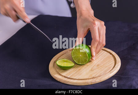 Aigre douce et lime ou de citron vert, la moitié couper avec le couteau sur la planche à découper Banque D'Images