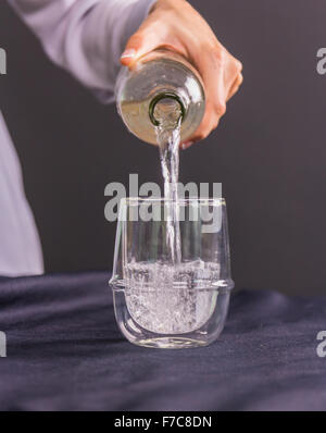 Gros plan sur la femme au foyer verser de l'eau dans le verre de Pichet filtre à eau Banque D'Images
