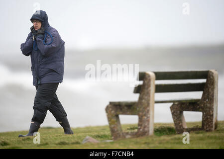 Un marcheur est soufflé dans des vents violents pendant une tempête au bord de Porthcawl Clodagh, Galles du Sud. Banque D'Images