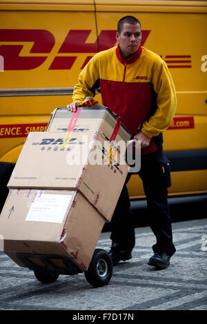 Employé de DHL livrant des colis, livreur de colis de DHL poussant le chariot Banque D'Images