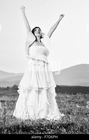 Happy young woman après la cérémonie du mariage cas s'amuser sur meadow en robe de mariage à la mode Banque D'Images