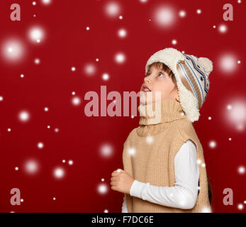 Concept de noël - girl in hat et sweater sur fond rouge jusqu'à la Banque D'Images