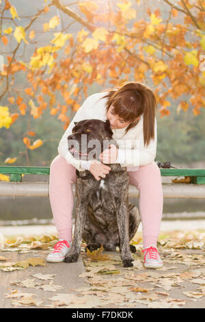 Jeune fille et sa Cane Corso chien bénéficiant d'automne ensoleillée journée au parc. Banque D'Images