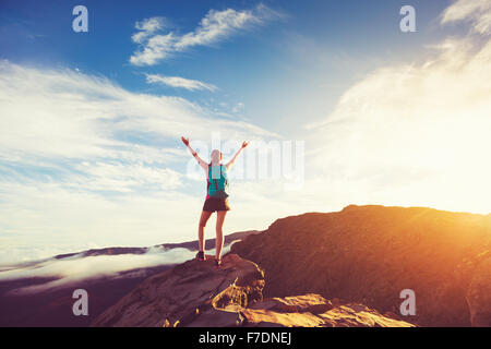 Happy Young Woman Hiker with open arms au coucher du soleil sur le sommet de la Montagne Banque D'Images