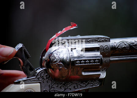 Close up of a child's silver old west jouet pistolet à capsules avec séquence de bouchons qui sortent de la partie supérieure de l'arme. Banque D'Images
