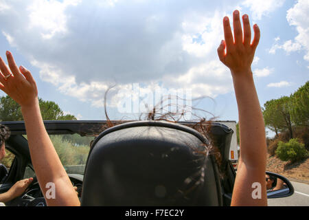 Road Trip in une voiture décapotable toit ouvert avec les cheveux au vent vu depuis le siège arrière autorisation modèle disponible Banque D'Images