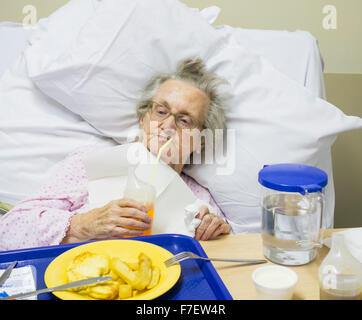 Quatre-vingt-dix ans female patient in hospital NHS boire de paille avec de la nourriture de l'hôpital sur bac. UK Banque D'Images