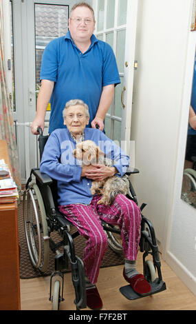 Carer mâle poussant une femme âgée en fauteuil roulant (pourrait être mère & fils) Banque D'Images