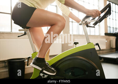 Remise en forme Cropped shot of woman on exercise bike à la salle de sport. Femme exerçant sur location dans un club de santé, l'accent sur leg Banque D'Images