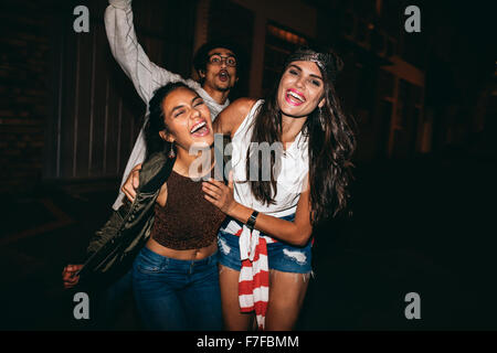 Portrait de trois jeunes amis avoir partie à l'extérieur. Cheerful young best friends hanging out at night. Banque D'Images