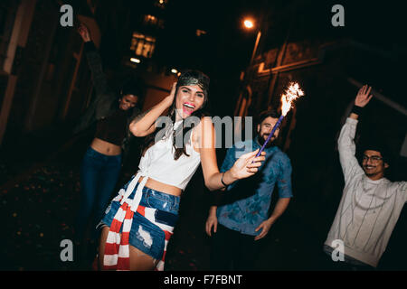 Portrait of young people celebrating avec feu d'artifice à l'extérieur de nuit, jeunes amis faire la fête avec les cierges magiques au 4ème de Banque D'Images