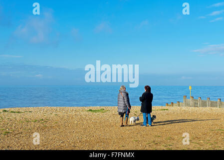 Deux femmes, avec les chiens, sur la plage de Whitstable, Kent, Angleterre, Royaume-Uni Banque D'Images
