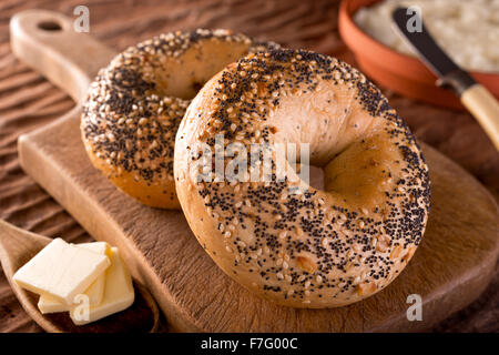 Bagels faits maison fraîchement cuits au four avec l'oignon, graines de sésame, graines de pavot, fromage à la crème et le beurre. Banque D'Images