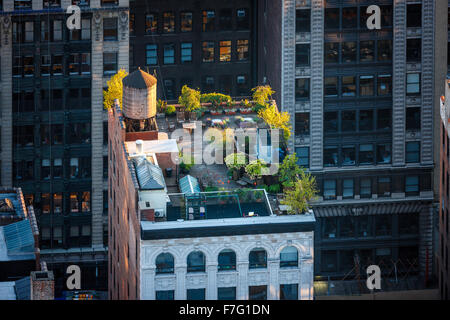 Vue aérienne d'un toit de Manhattan au coeur de New York City. Jardin sur le toit à Chelsea avec arbres et éclairée par le réservoir d'eau en bois Banque D'Images