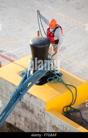 Un navire de croisière mexicaine liens dockers amarres à un grand bollard attaché à un quai à Cancun, au Mexique. Banque D'Images