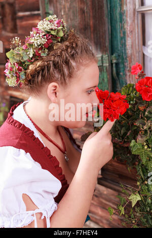 Portrait d'une jeune femme en dirndl odeur d'un géranium Banque D'Images