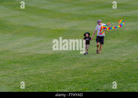 Un homme et son enfant marchant sur l'herbe à l'Arboretum national de Canberra, en Australie, avec un cerf-volant Banque D'Images