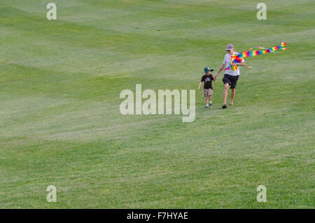 Un homme et son enfant marchant sur l'herbe à l'Arboretum national de Canberra, en Australie, avec un cerf-volant Banque D'Images