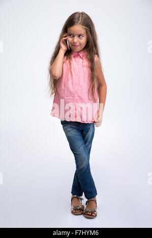 Portrait of a cute little girl talking on the phone isolé sur fond blanc Banque D'Images