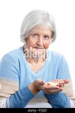 Femme âgée holding poignée de pilules prescrites over white Banque D'Images