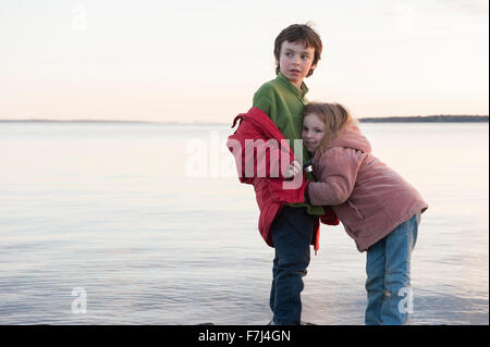 Little girl hugging son frère au bord de l'eau Banque D'Images